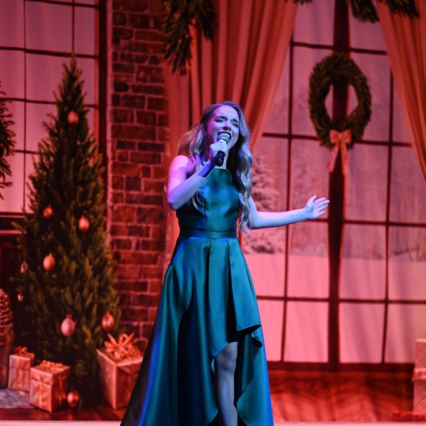 Woman in long green dress singing at the winter showcase