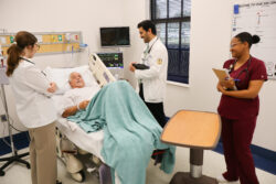 ACOM medical students and a Wallace nursing student assess a standardized  patient during an educational simulation