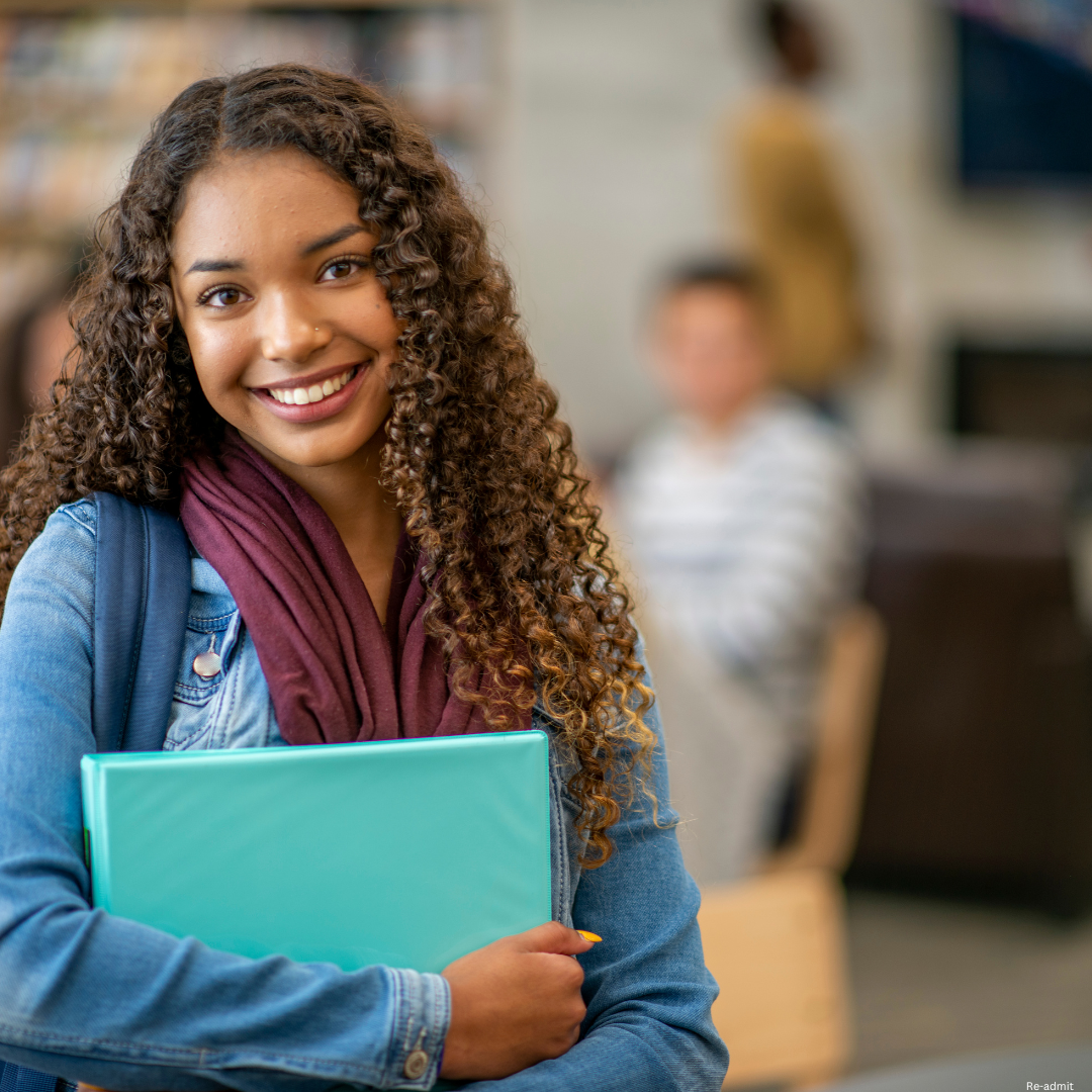 Female student smiling holding a notebook.